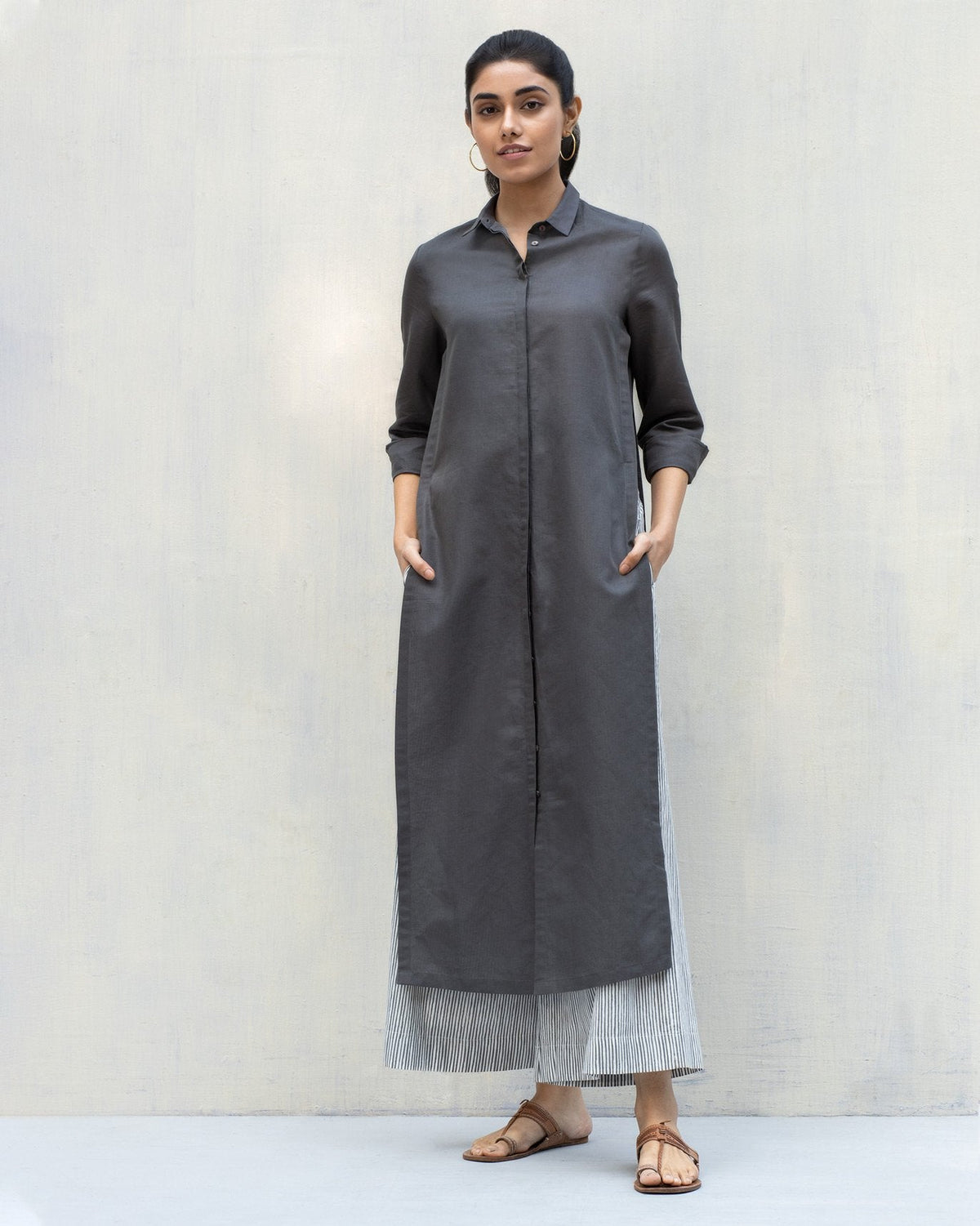 Person with hands in pockets, wearing a long charcoal Many Moons Kurta.