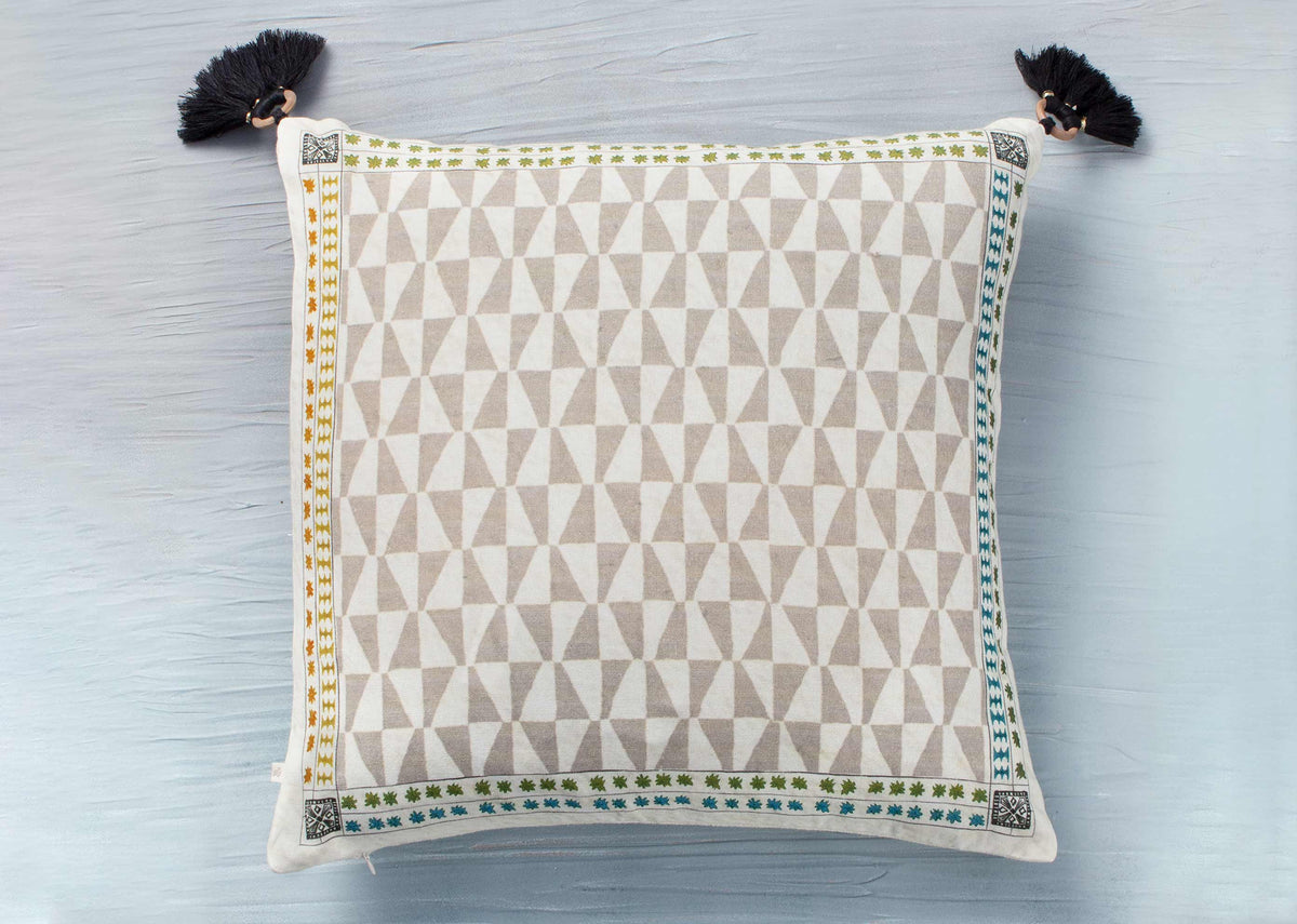 Cushion cover with a beige triangle pattern and tasselled corners.
