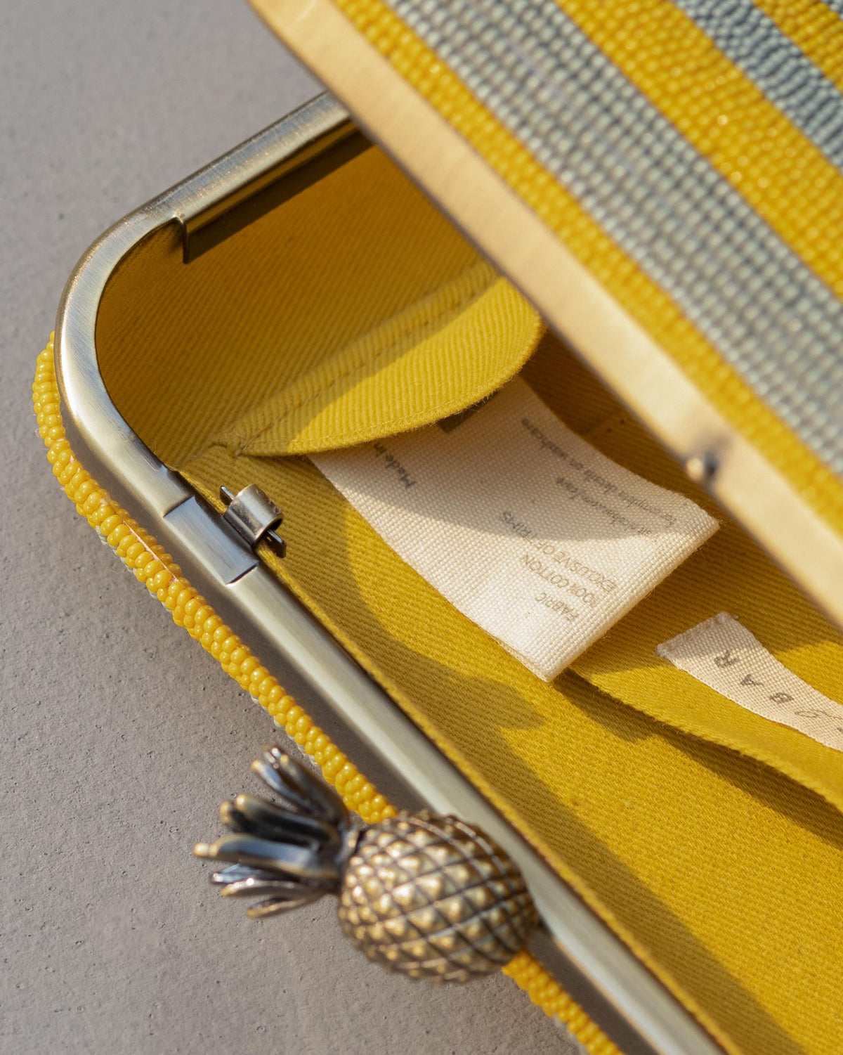 Close-up of the Ananas clutch interior showing a care label.