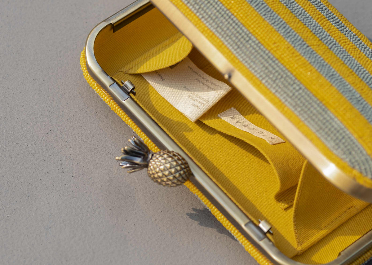 Close-up of the Ananas clutch's pineapple clasp and open yellow lining.