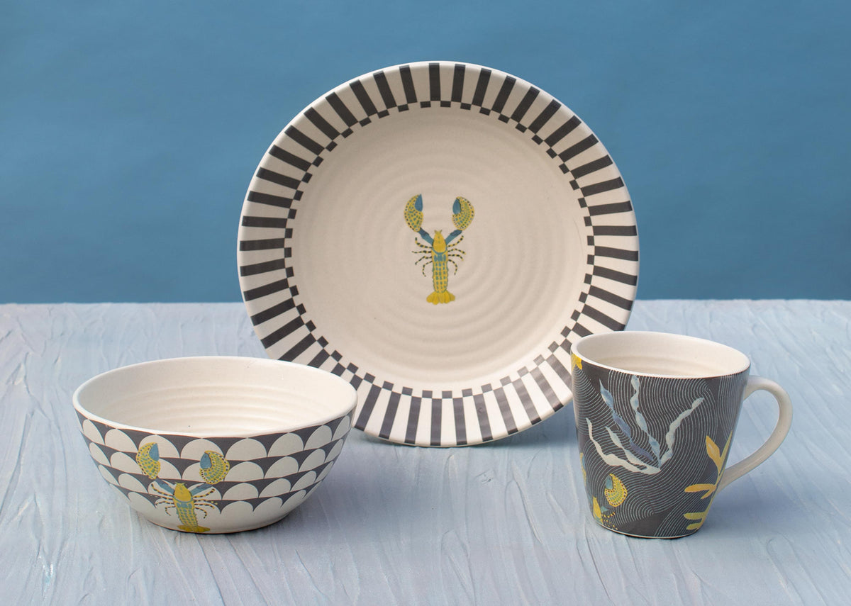 Champa Breakfast Set laid out, with a lobster-motif plate, scalloped bowl and leaf-print mug.