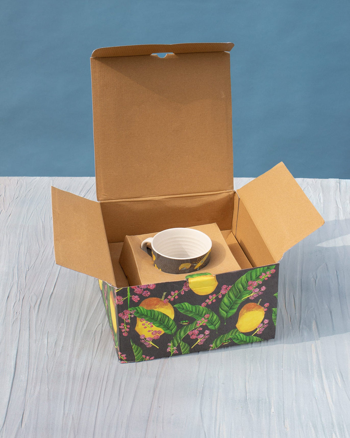 Open lemon-print gift box with a Champa Breakfast Set mug inside.