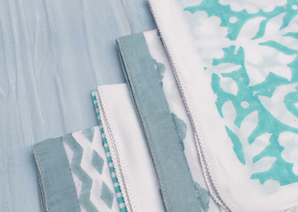 Close-up of Allamanda Dinner Napkin showing its teal floral print and border.