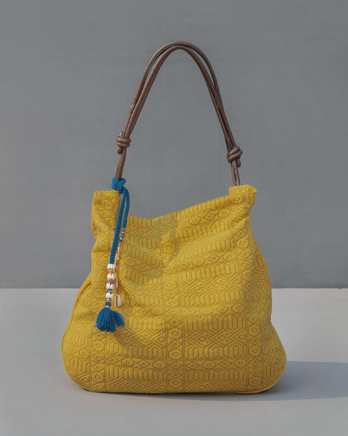 Yellow Nomad Tote with a geometric pattern and brown leather handles.