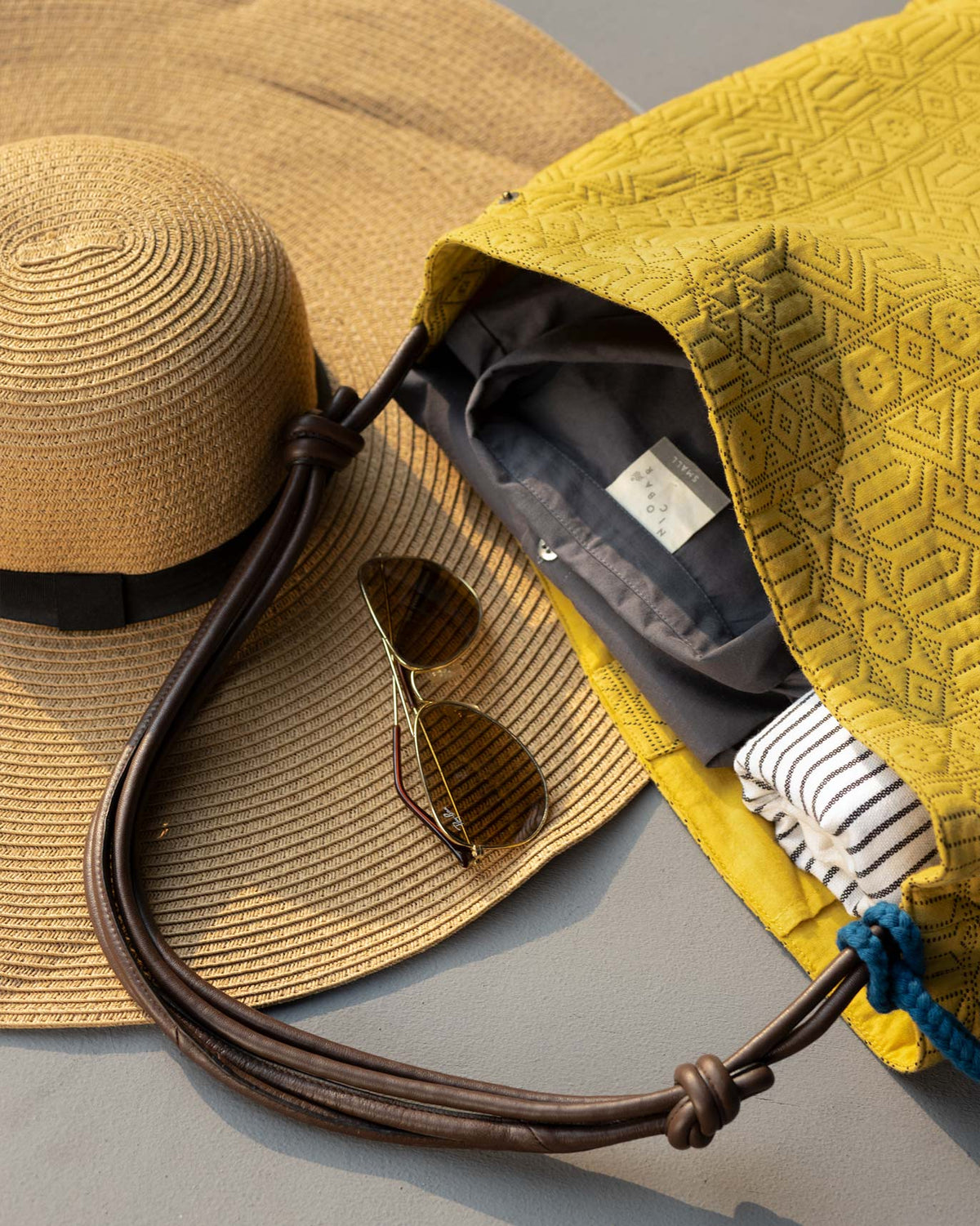 Nomad Tote open on a surface, showing its yellow lining and leather strap.