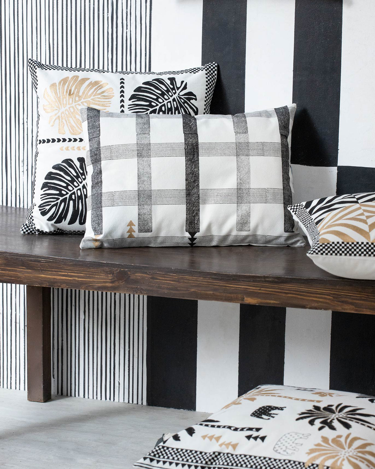 Check Stripe Lumbar Pillow Cover in black and white, on a wooden bench with other cushions.