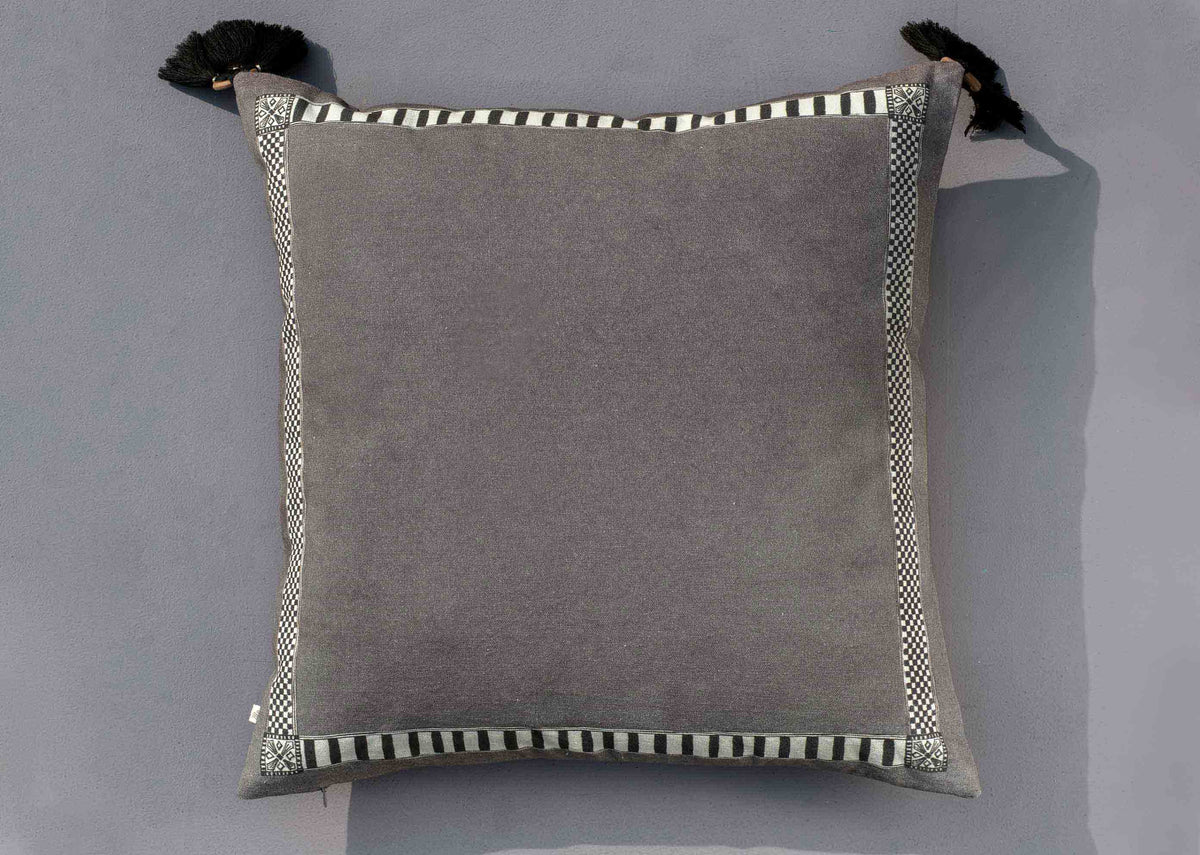 Back of an Aam Cushion Cover, plain grey with tassels at the corners.