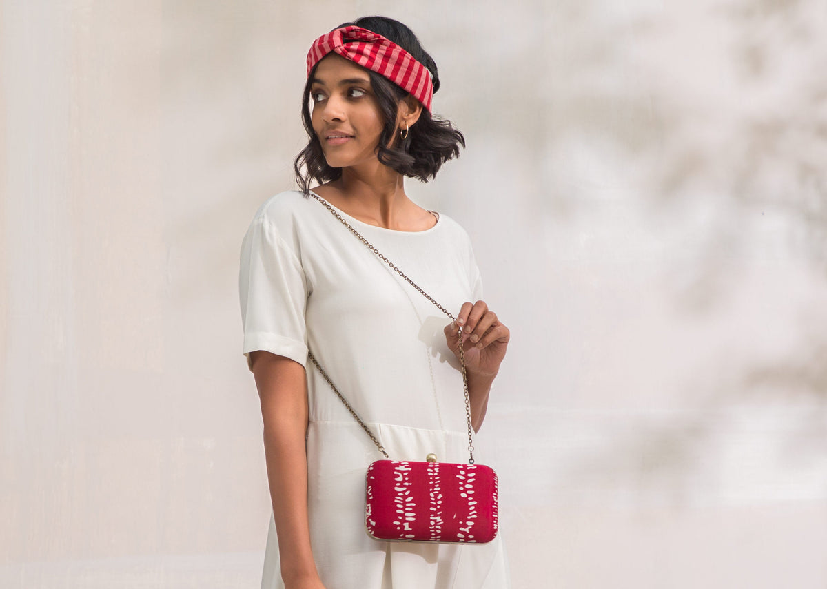 Person carrying a red Martini Clutch by its chain strap.