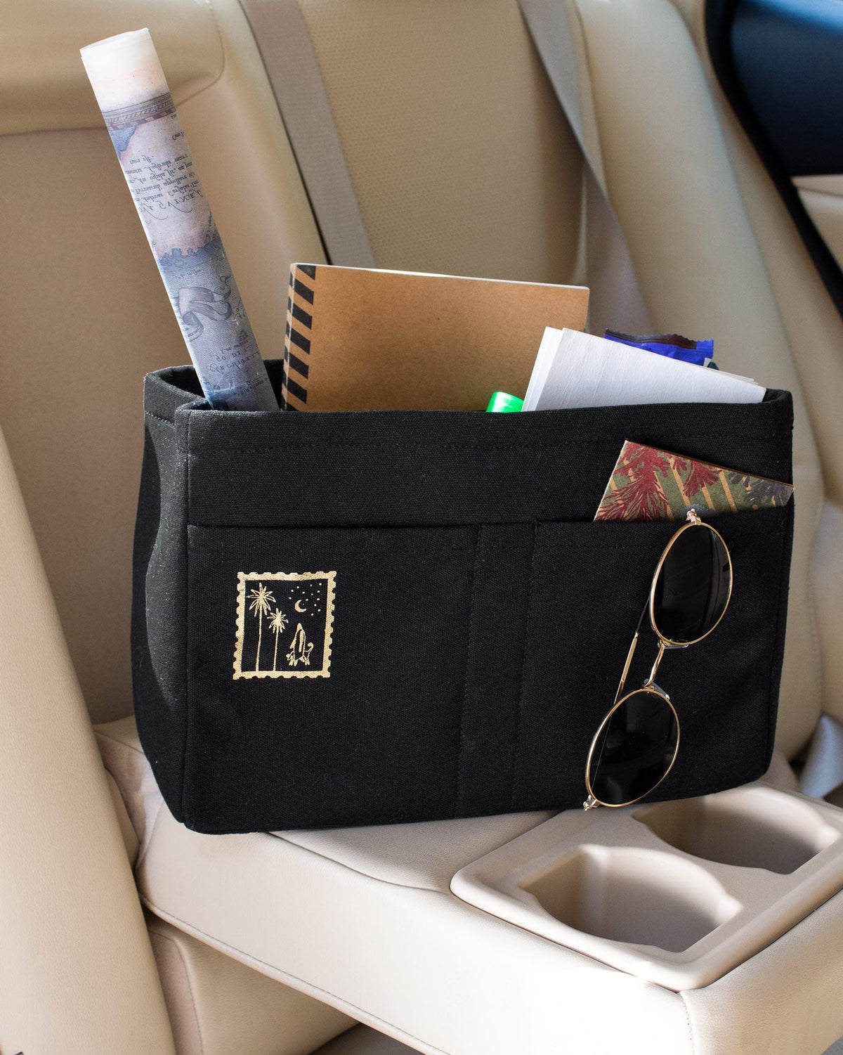 Black Musafir Zenbu organiser holding a rolled map, notebook and sunglasses.