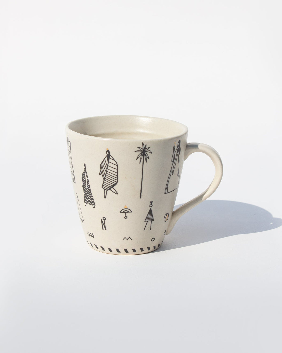 Side view of Musafir Mug with black figure drawings and a palm tree.