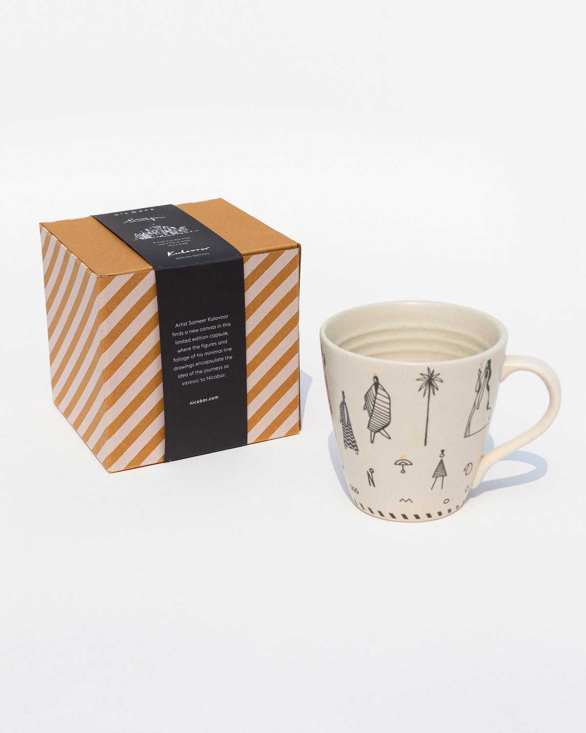 Musafir Mug beside its striped gift box, showing black figure drawings.