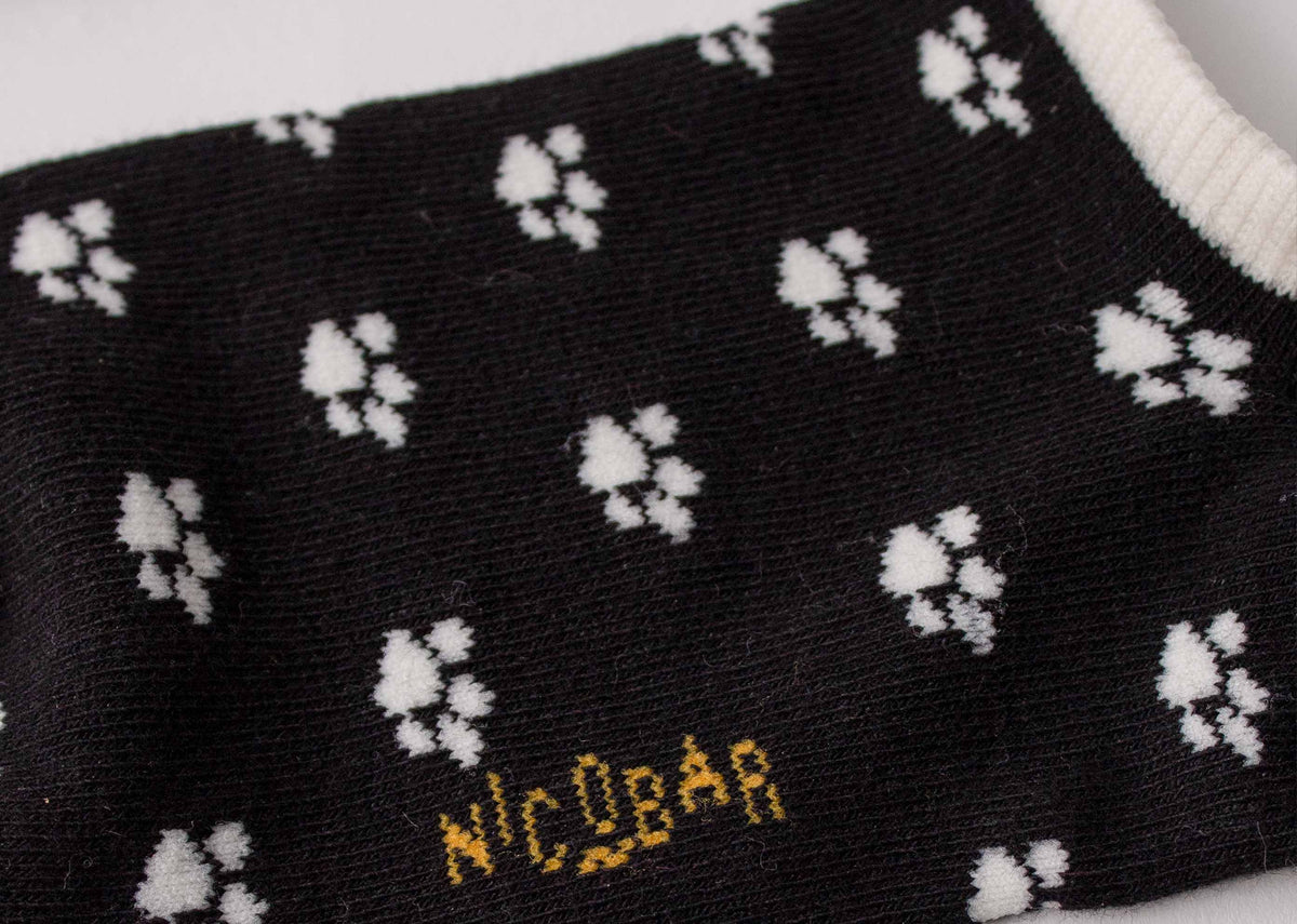 Close-up of the Paw Print Socks showing white paw prints and a yellow Nicobar logo.