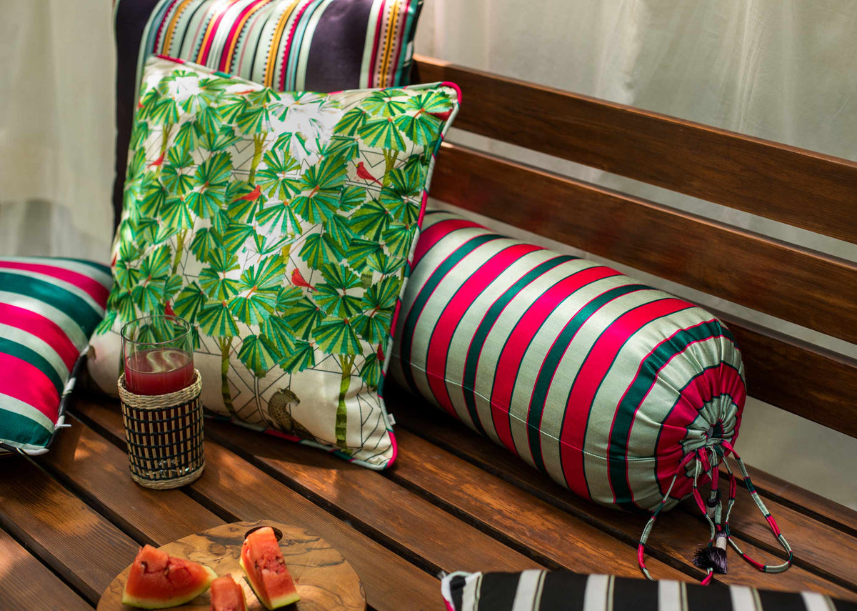 Cheetah Cushion Cover with a green palm print, on a wooden bench with other cushions.
