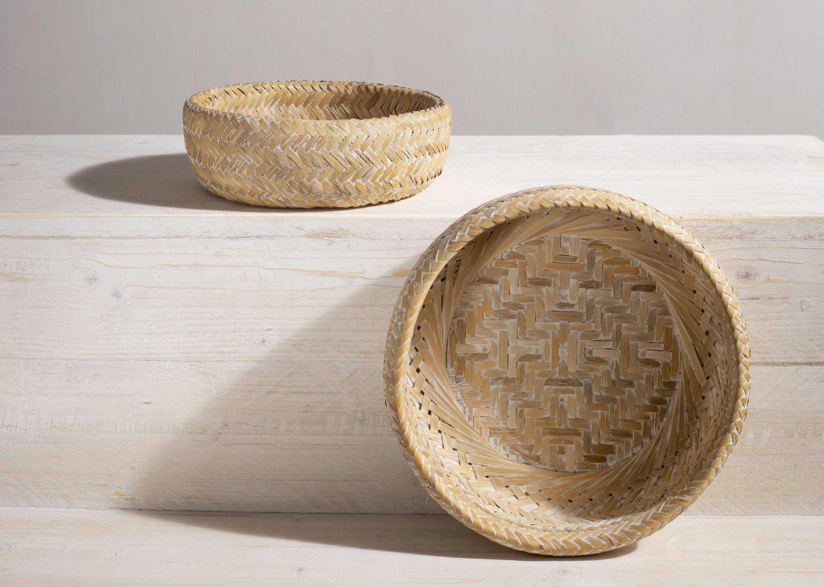 Two Double Walled Bamboo Fruit Baskets placed on a pale wooden surface.