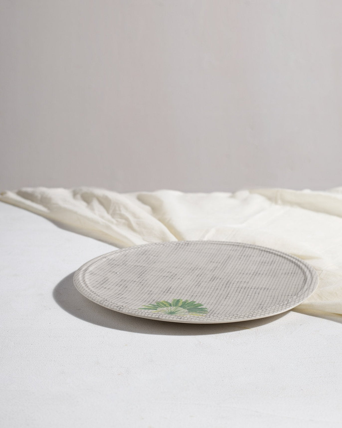 Madagascar dinner plate showing its shallow rim and palm leaf motif.