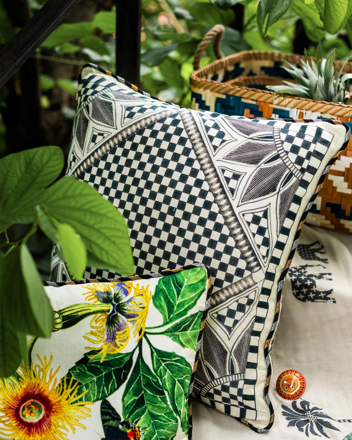 Arabesko cushion cover in charcoal leaning beside a floral cushion.
