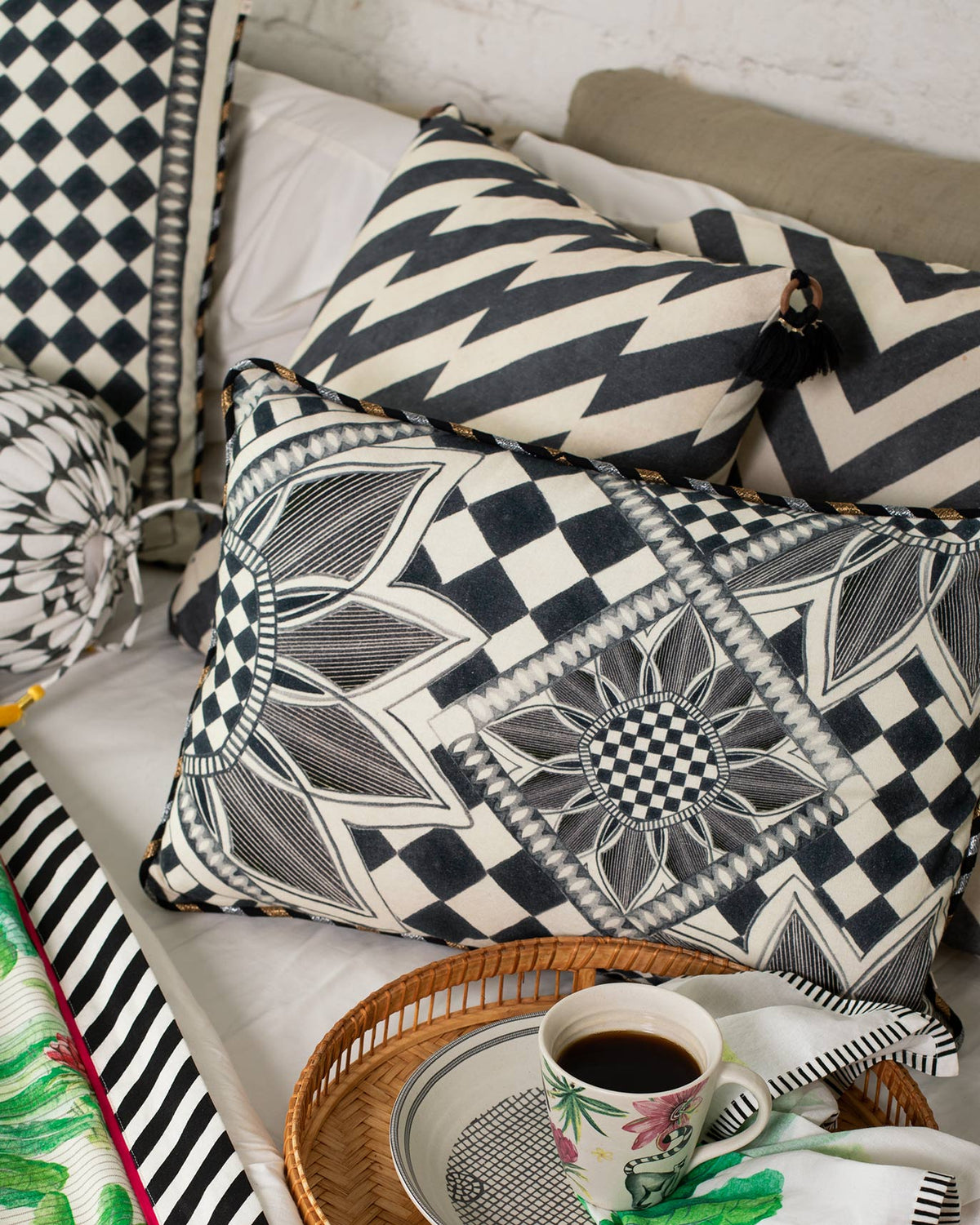 Arabesko Lumbar Cushion Cover in charcoal, styled on a bed with other cushions.