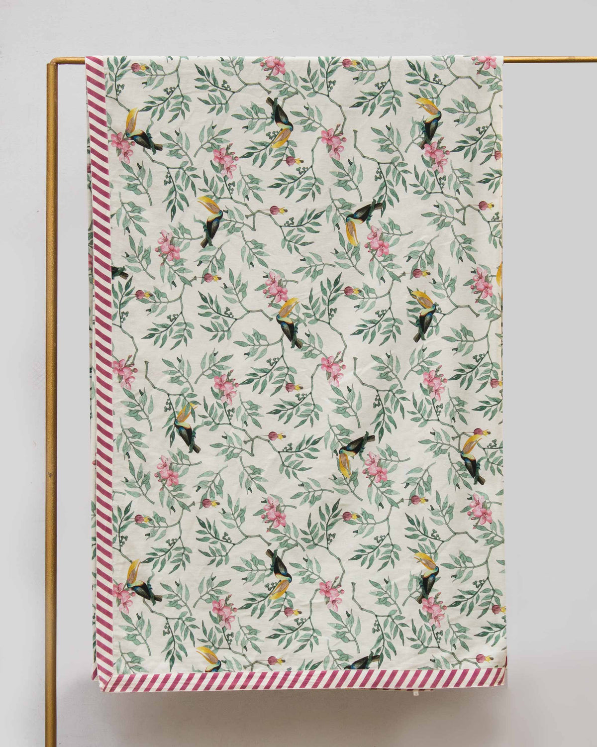 Ivory Nakano king bed cover with toucan foliage print and a pink striped border.