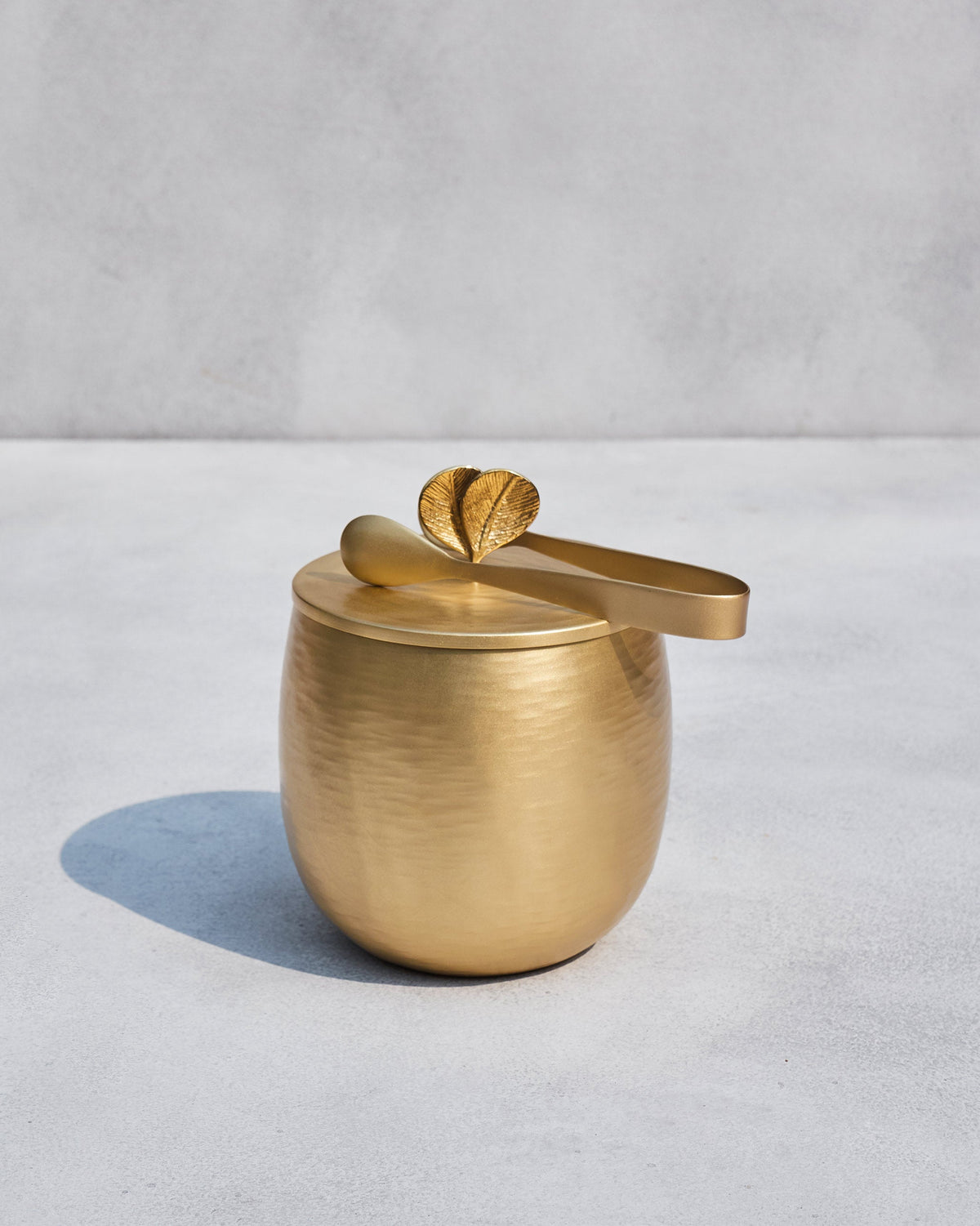 Champa ice bucket with tongs resting on its leaf-handled gold lid.