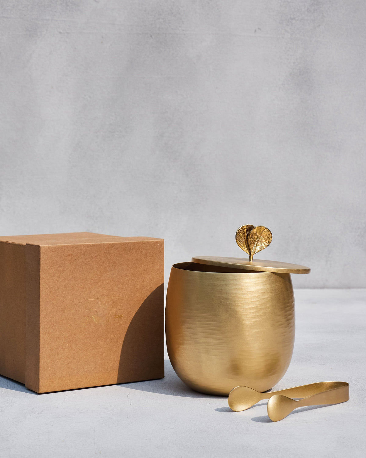 Champa ice bucket, lid, and tongs beside a brown kraft gift box.