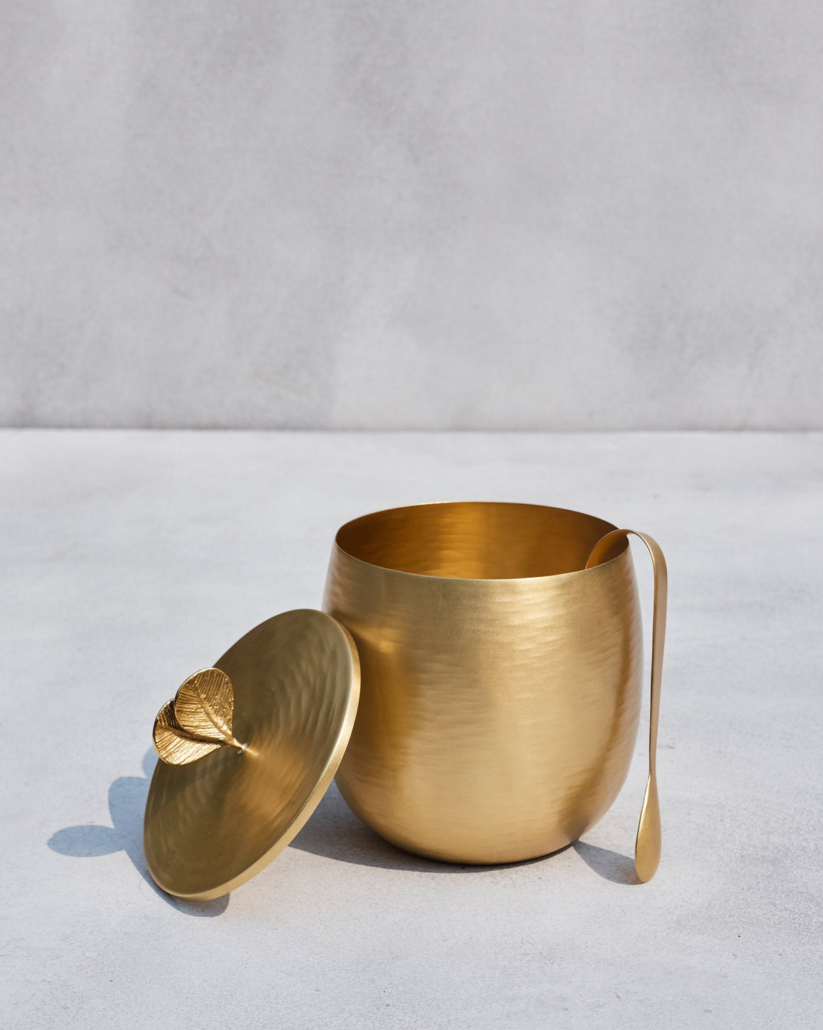 Open Champa gold ice bucket with tongs on the rim and lid beside it.