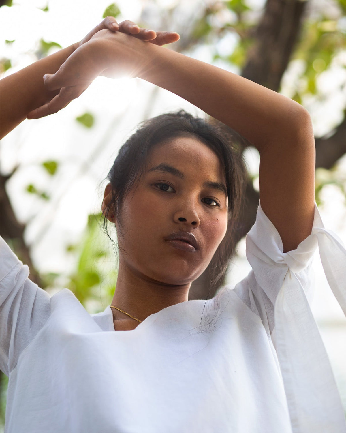 Person with arms raised, wearing a white A-line Dress with a tied sleeve.