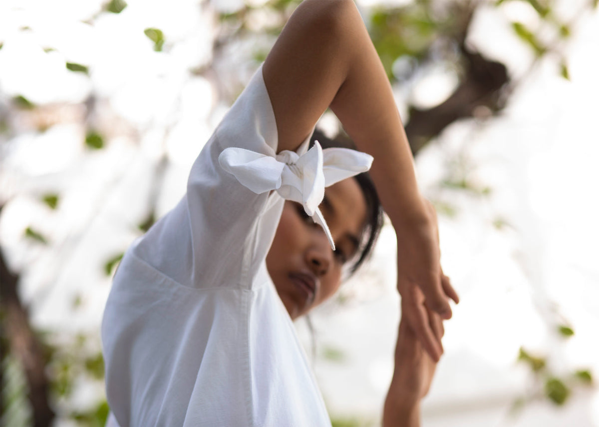Close-up of a white A-line Dress sleeve with a bow tied at the cuff.