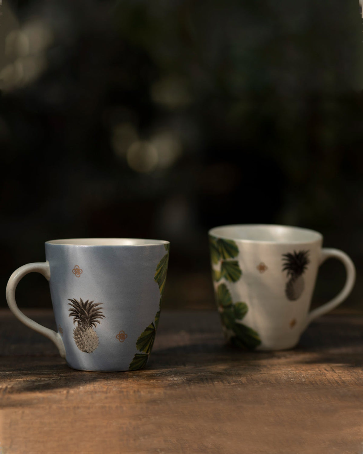 Oyster Bay mugs side by side, each with a pineapple motif.