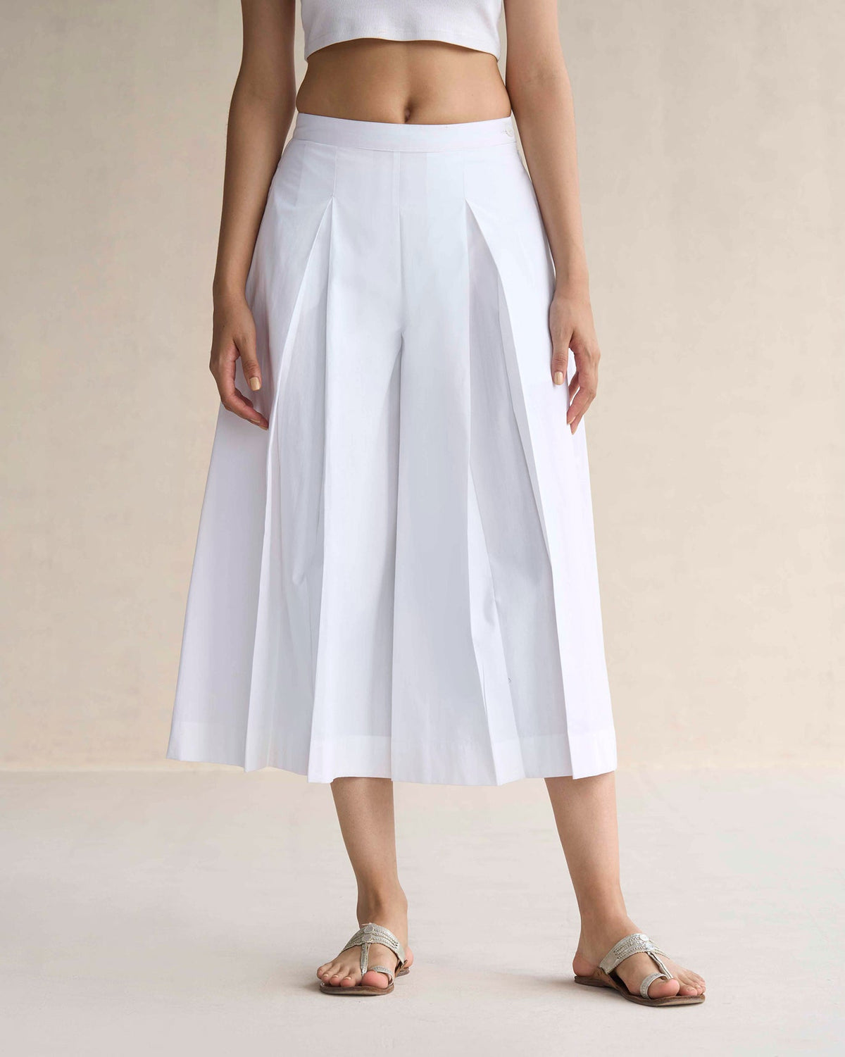 White pleated flare culottes with deep box pleats and wide mid-calf legs.