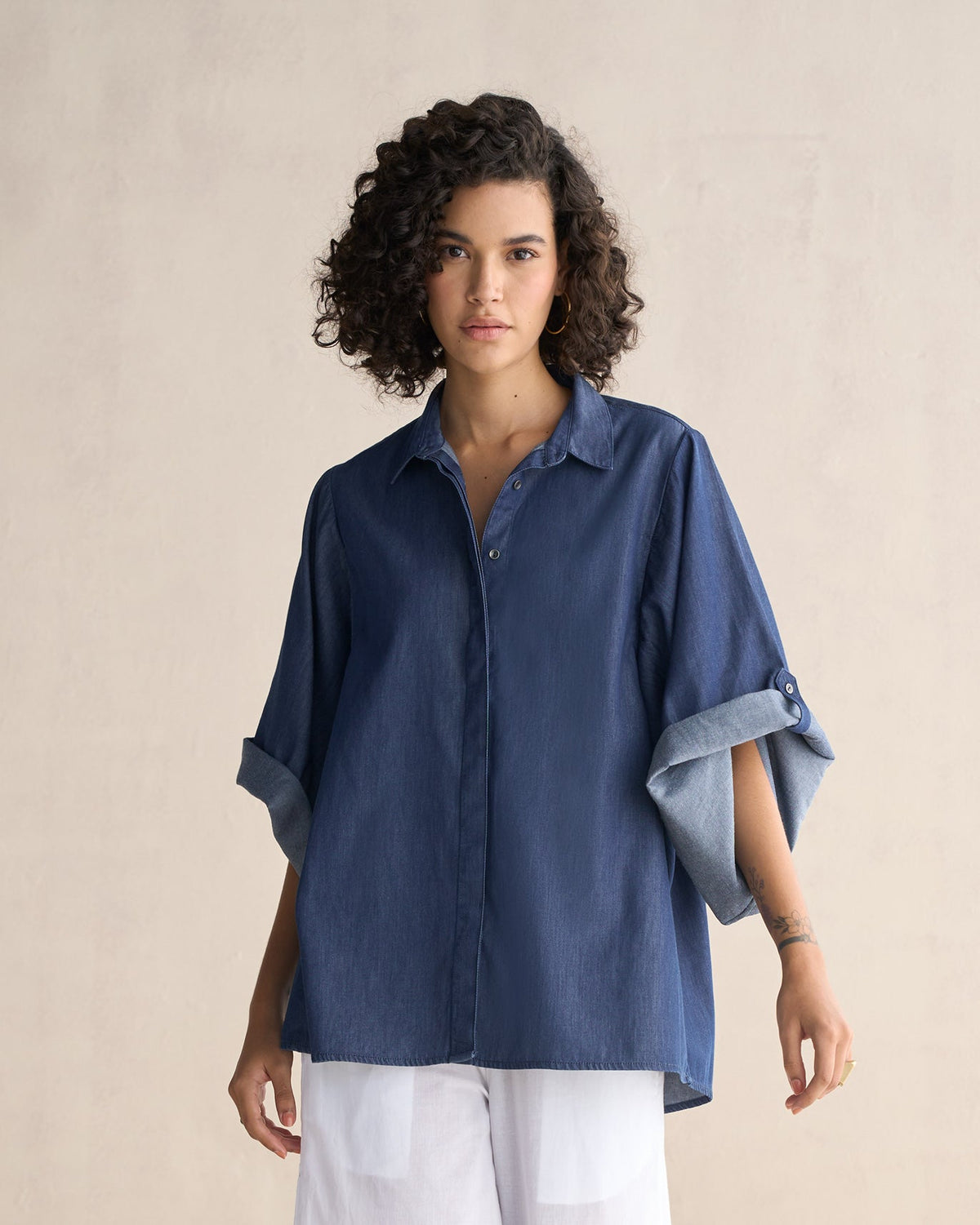 Person wearing the Drop Armhole Shirt in blue with rolled sleeves.
