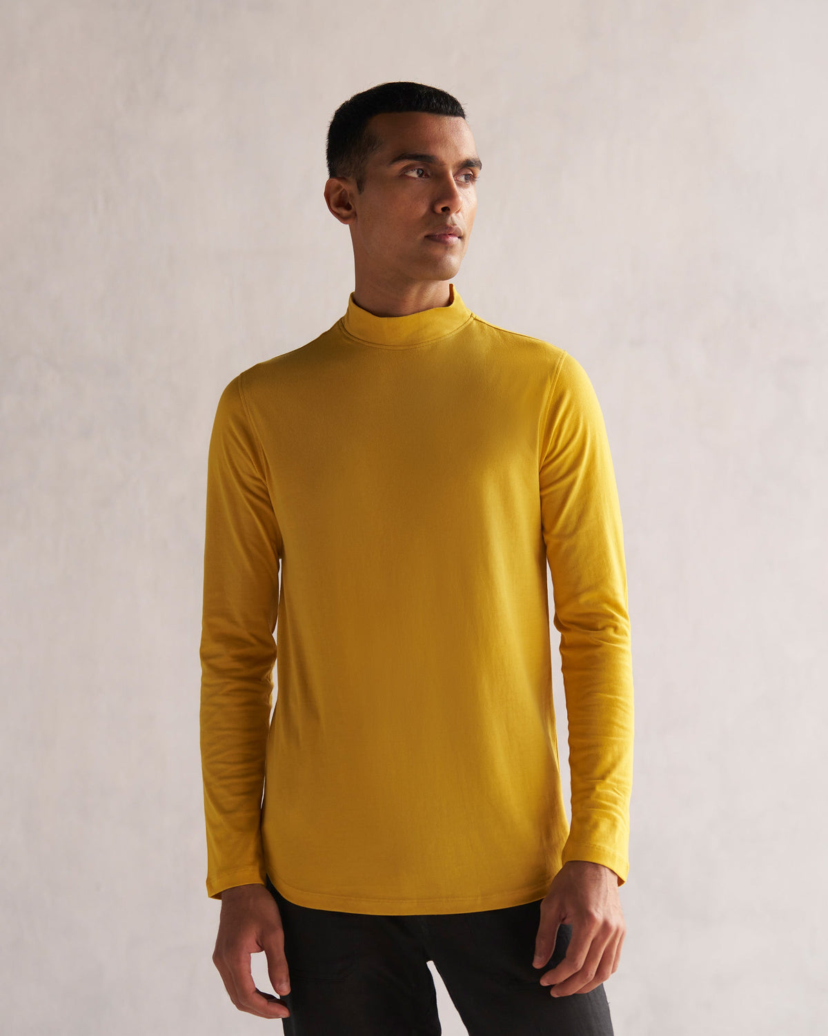 Person wearing a mustard turtle neck t-shirt with long sleeves.