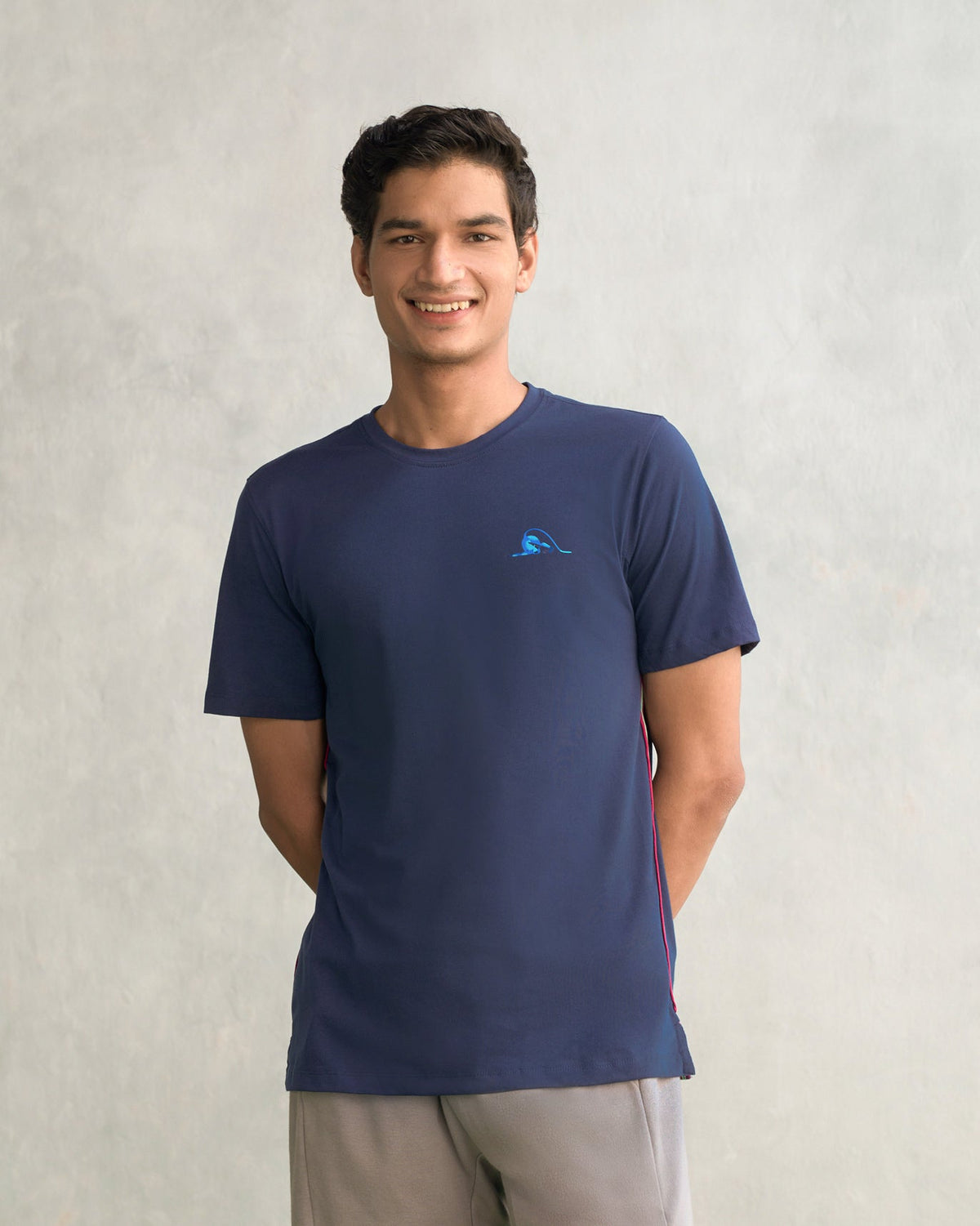 Person wearing a navy Club Crew Neck T-shirt with a small blue embroidered graphic on the chest.