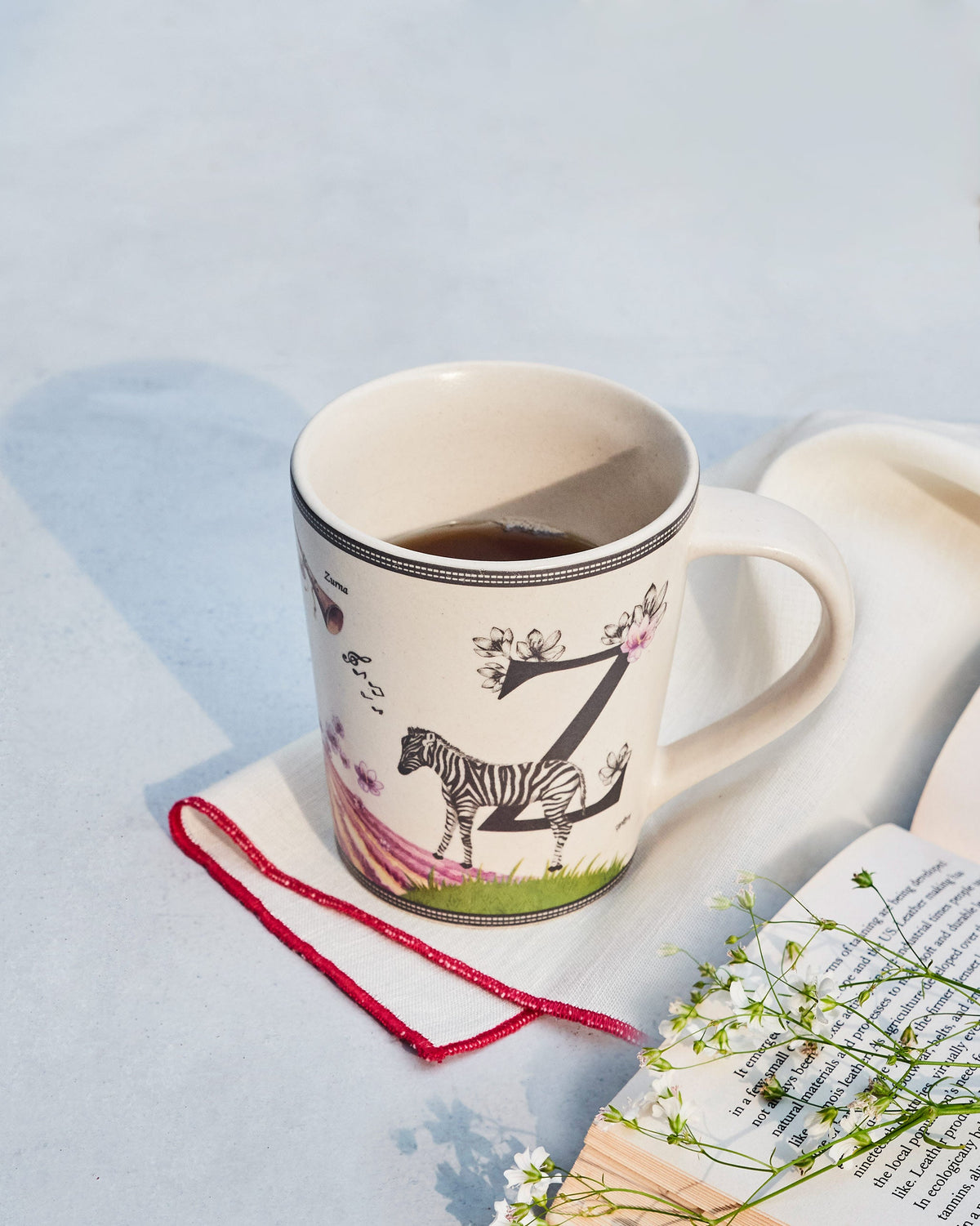 Cream Zafran alphabet mug with letter Z, zebra and flowers, filled with coffee.