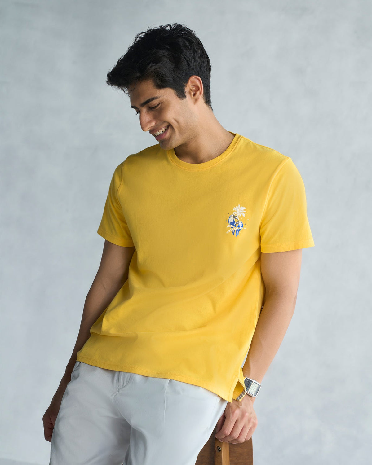 Person wearing a yellow Toucan T-shirt with a small embroidered motif on the chest.