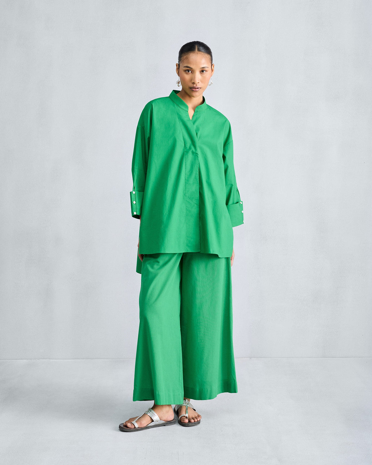 Person standing in a green Cirrus shirt with a V-notch collar, shown full length.