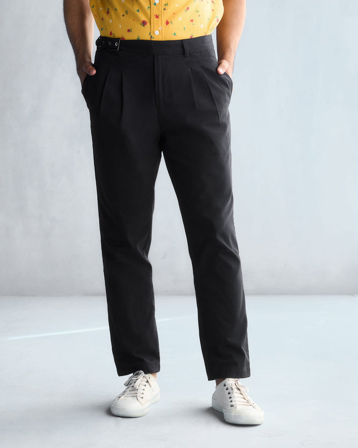 Person wearing black Trunk & Twill trousers with pleated front and side buckle waist.