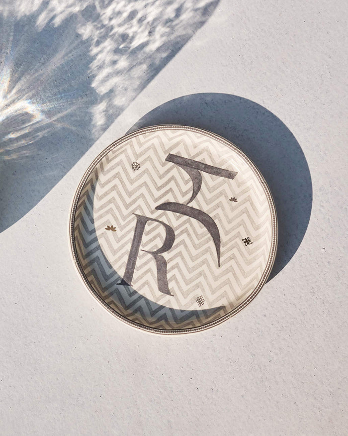 Akshar Coaster - R laid flat, showing the grey R glyph on a chevron pattern.