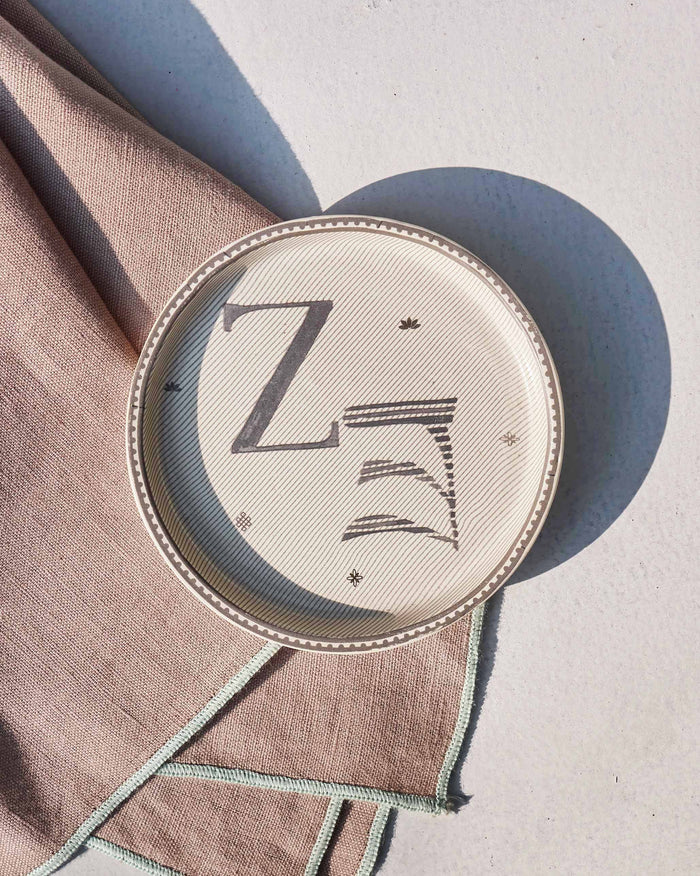 Akshar Coaster - Z laid flat, showing the grey Z glyph and beaded rim.