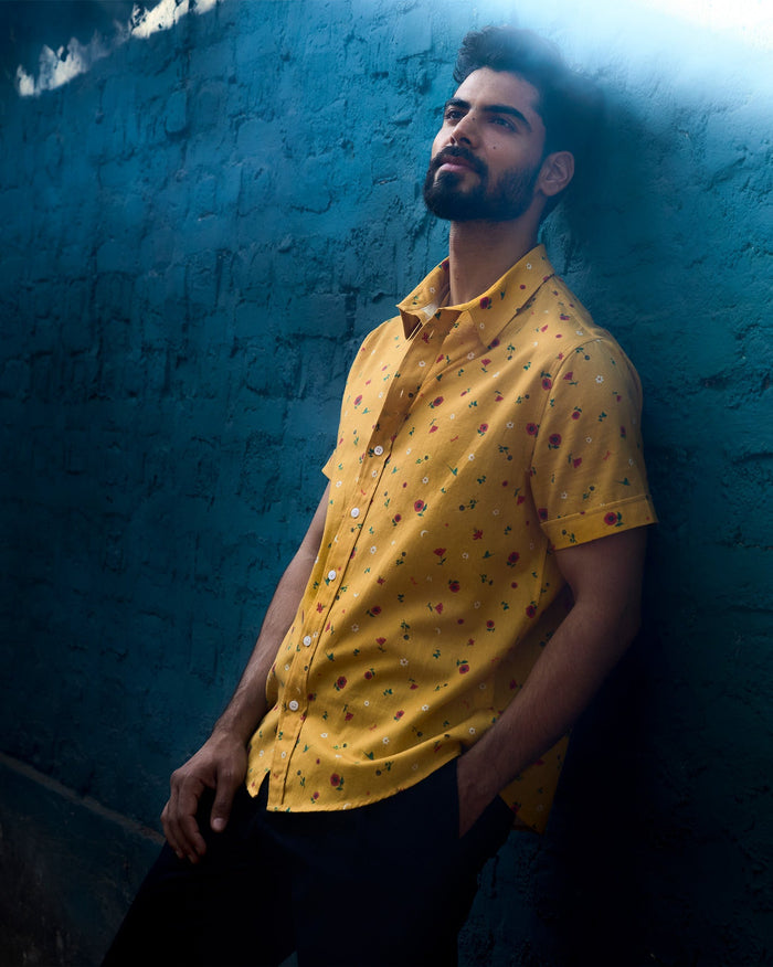 Person wearing an ochre Half Sleeve Shirt with a small red floral print.