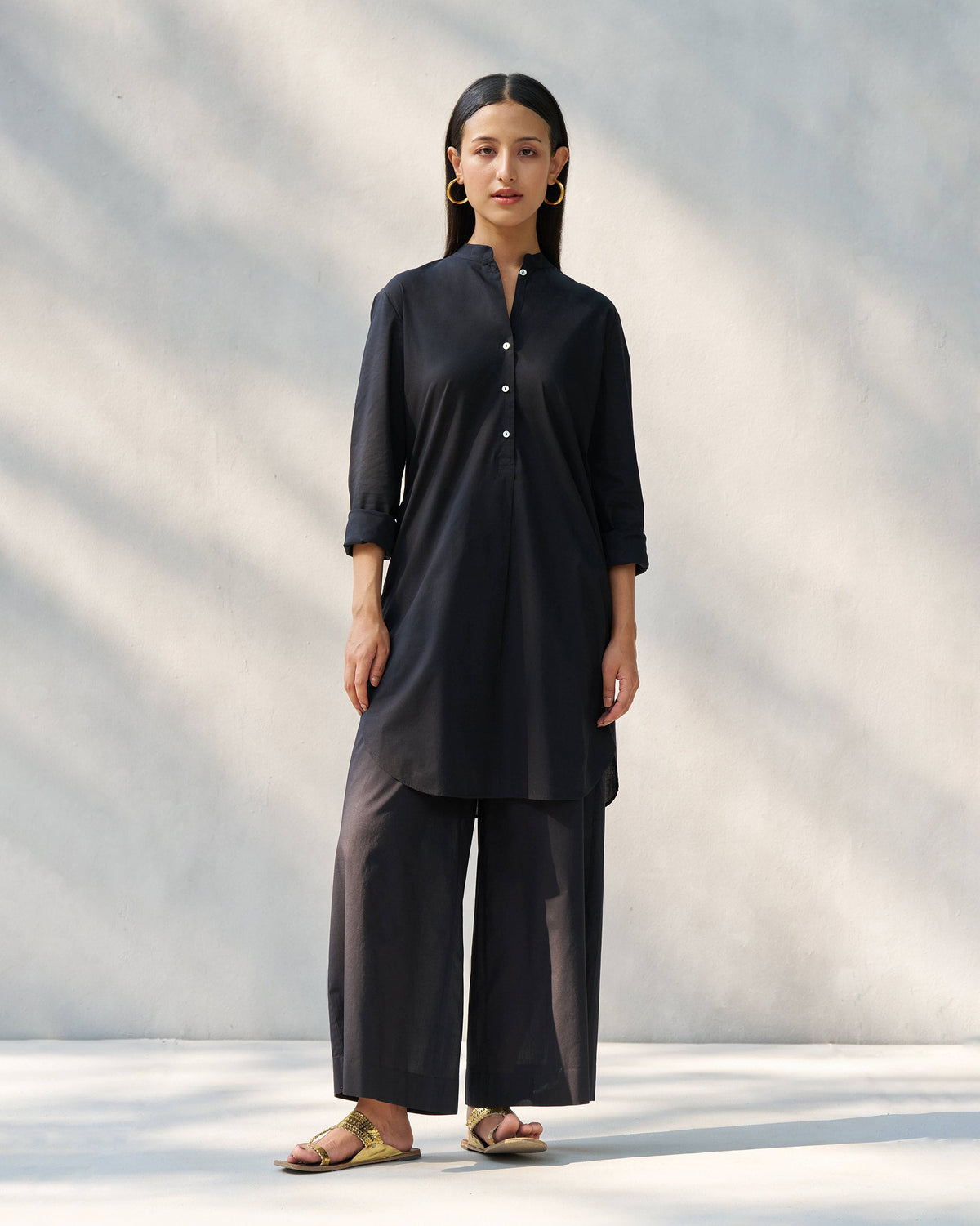 Person wearing a black Stone set with a mandarin collar tunic and wide pants.