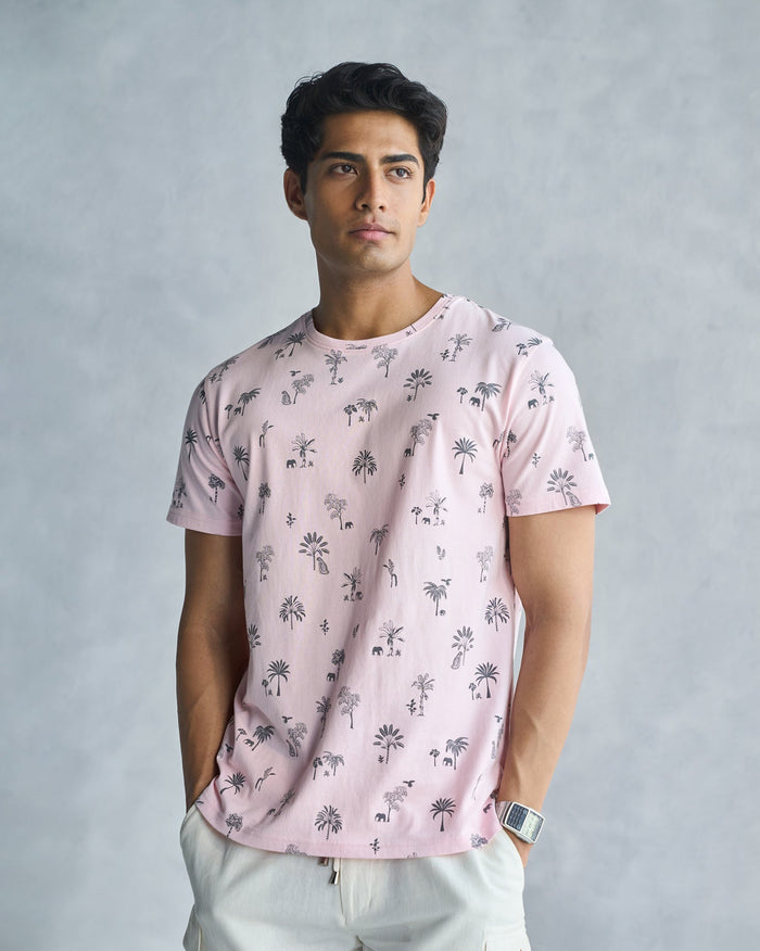 Person wearing a soft pink Jungle T-shirt with a navy palm tree print.
