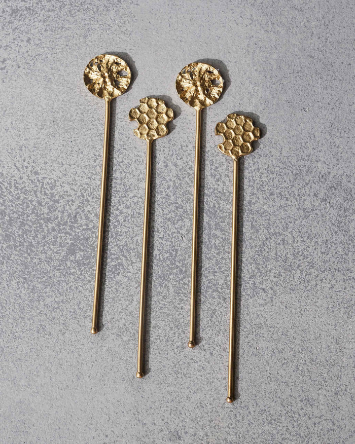 Set of four gold Dawa stirrers with textured round and honeycomb heads.