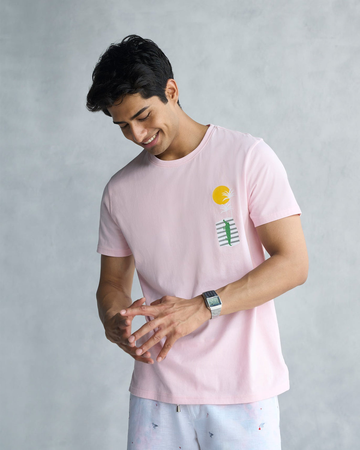 Person wearing a soft pink See Ya Later Alligator t-shirt with a sun and alligator print.