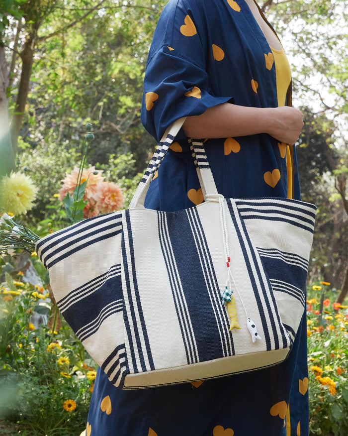 Person carrying the Serenity Tote on one shoulder, in navy and ivory stripes.