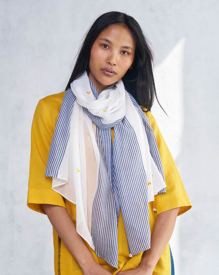 Person wearing a white Dokai Scarf with navy stripes and small yellow motifs.
