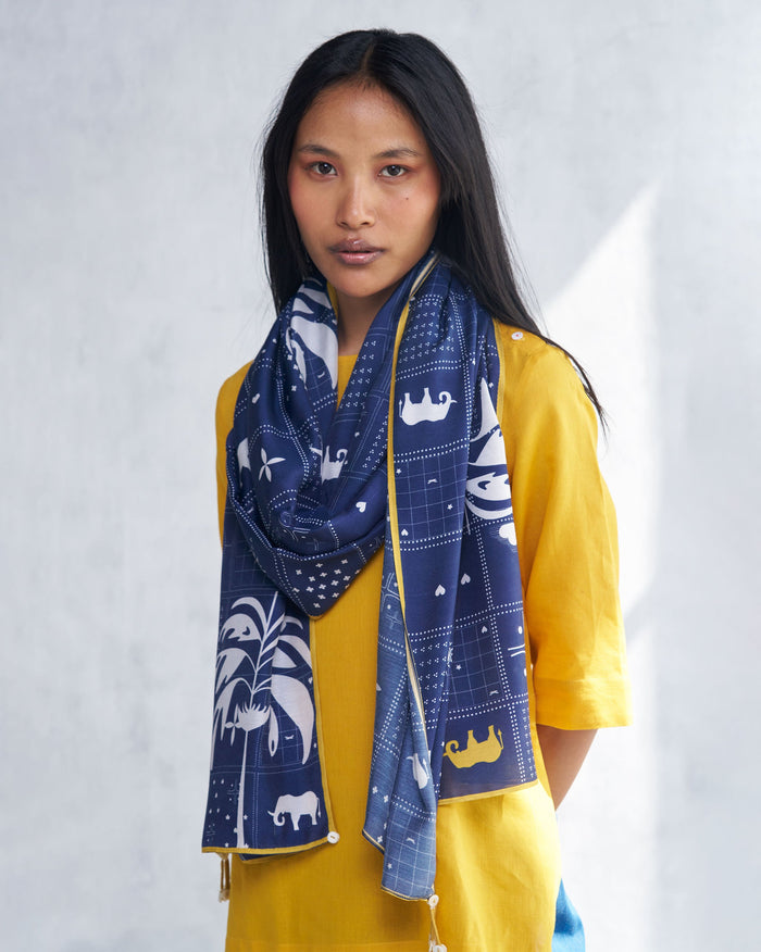 Person wearing a navy Parken scarf with white elephant and palm motifs.