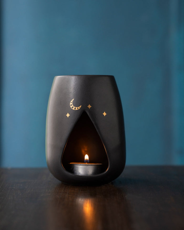 Sher diffuser with a gold moon and stars, shown with a lit tea-light.