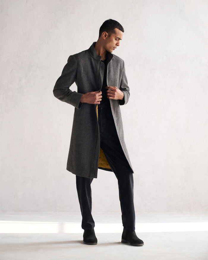 Person wearing a grey Long Jacket with a stand collar.