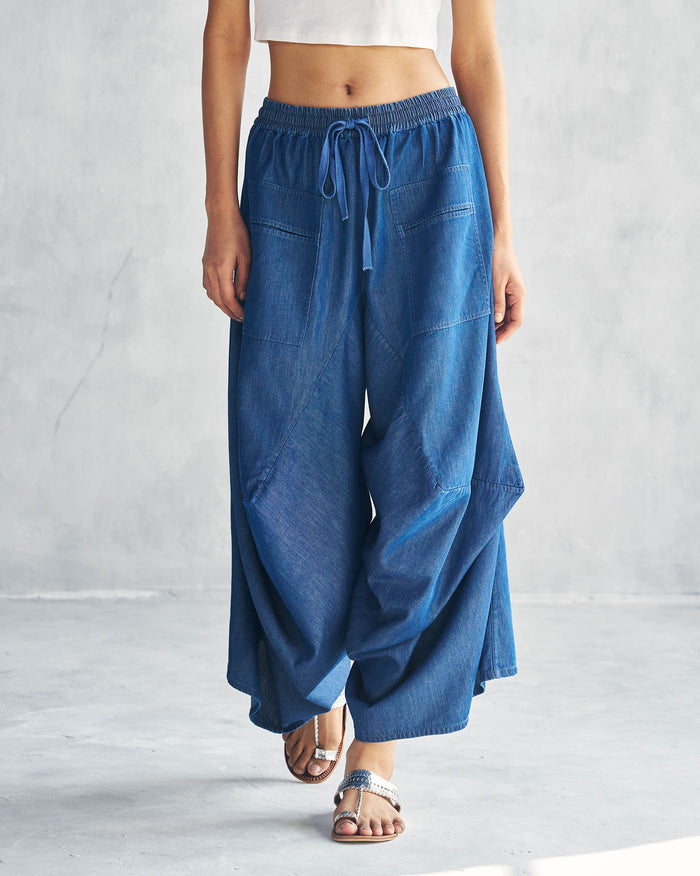 Person wearing blue Yoka Trousers with a drawstring waist and patch pockets.