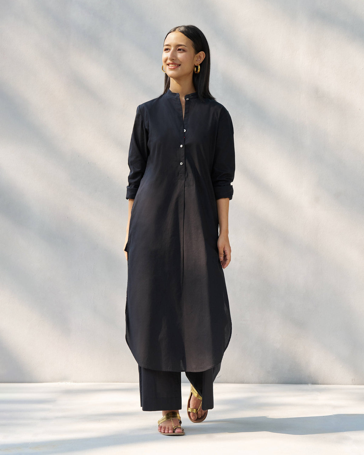 Person wearing a black long kurta set with matching wide-leg pants.